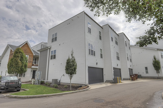 view of building exterior with central AC unit and a garage