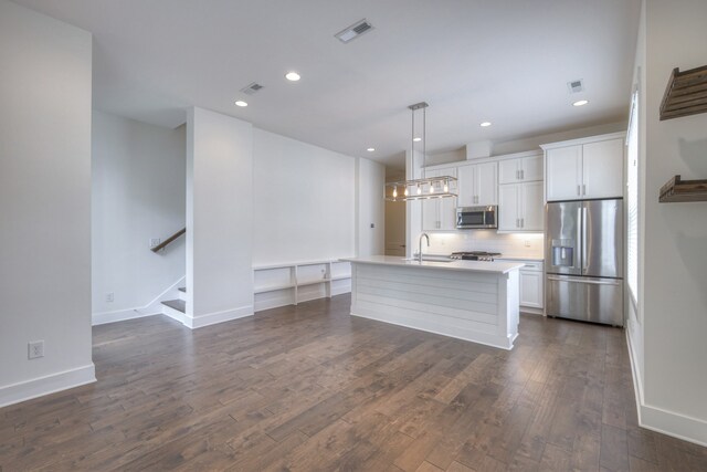 kitchen with a kitchen island with sink, appliances with stainless steel finishes, dark hardwood / wood-style floors, and white cabinetry