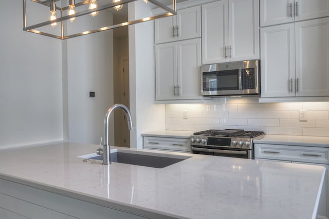 kitchen featuring light stone counters, appliances with stainless steel finishes, and white cabinetry