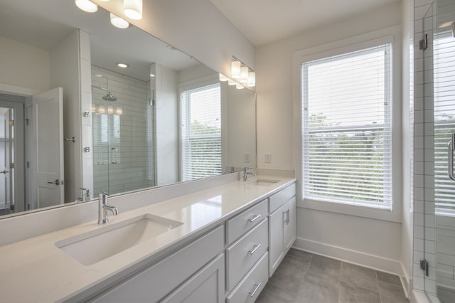 bathroom with vanity, a shower with shower door, plenty of natural light, and tile patterned floors