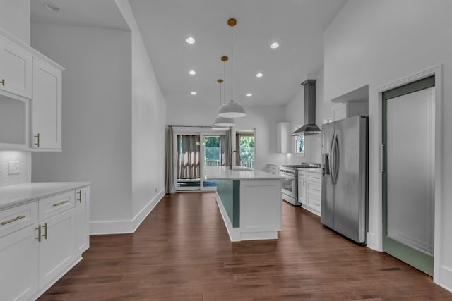 kitchen with appliances with stainless steel finishes, wall chimney exhaust hood, dark wood-type flooring, pendant lighting, and white cabinetry