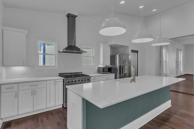 kitchen featuring stainless steel appliances, dark wood-type flooring, decorative light fixtures, white cabinets, and an island with sink