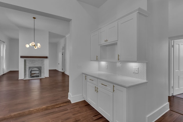 kitchen with dark hardwood / wood-style flooring, tasteful backsplash, decorative light fixtures, a fireplace, and white cabinetry