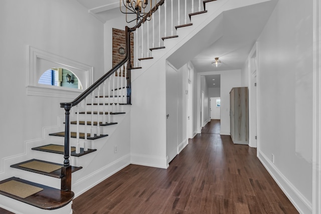 foyer entrance with dark hardwood / wood-style floors and an inviting chandelier