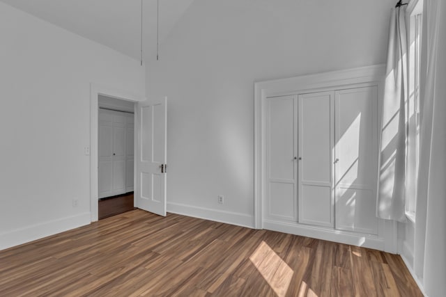 unfurnished bedroom with dark wood-type flooring and lofted ceiling