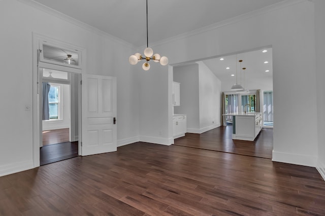 unfurnished dining area featuring sink, an inviting chandelier, dark hardwood / wood-style flooring, crown molding, and a towering ceiling