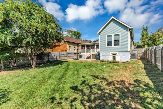 back of property with a lawn, central air condition unit, and a sunroom