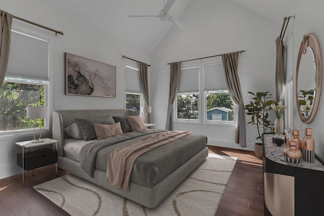 bedroom featuring dark hardwood / wood-style floors, ceiling fan, high vaulted ceiling, and multiple windows