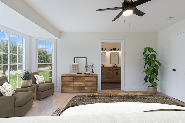 bedroom featuring ceiling fan, light hardwood / wood-style flooring, and connected bathroom