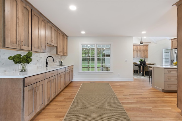 kitchen featuring light hardwood / wood-style floors, tasteful backsplash, sink, a kitchen bar, and stainless steel refrigerator