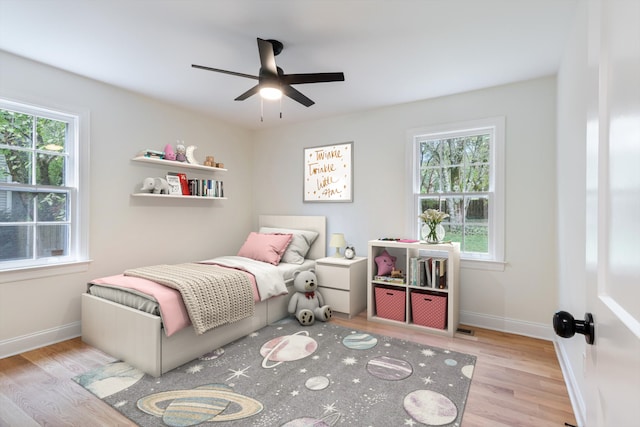 bedroom featuring ceiling fan, light wood-type flooring, and multiple windows