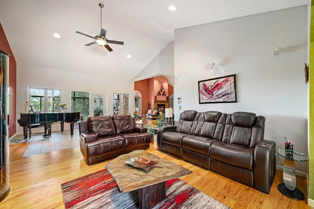 living room featuring ceiling fan, light hardwood / wood-style floors, and high vaulted ceiling