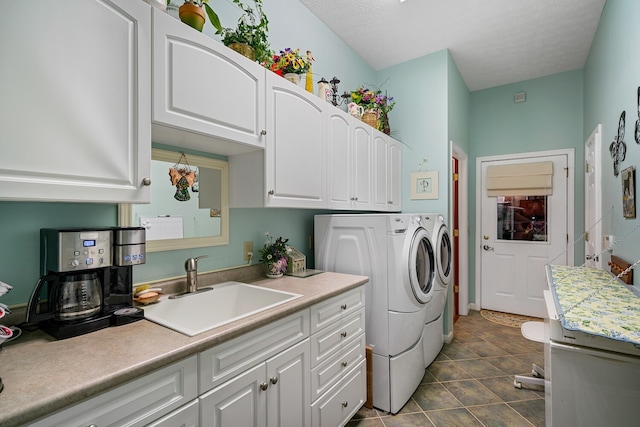 laundry area with a textured ceiling, sink, washer and dryer, and dark tile patterned flooring