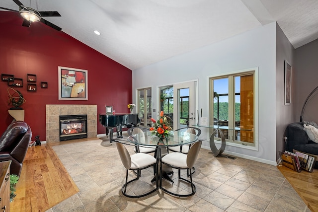 dining room featuring ceiling fan, lofted ceiling, light hardwood / wood-style floors, and a tile fireplace