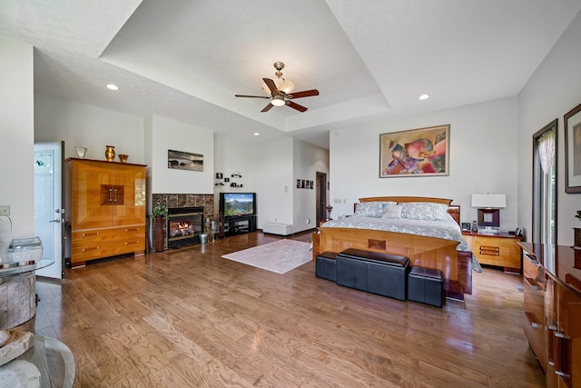 bedroom with a textured ceiling, a tray ceiling, ceiling fan, and hardwood / wood-style flooring