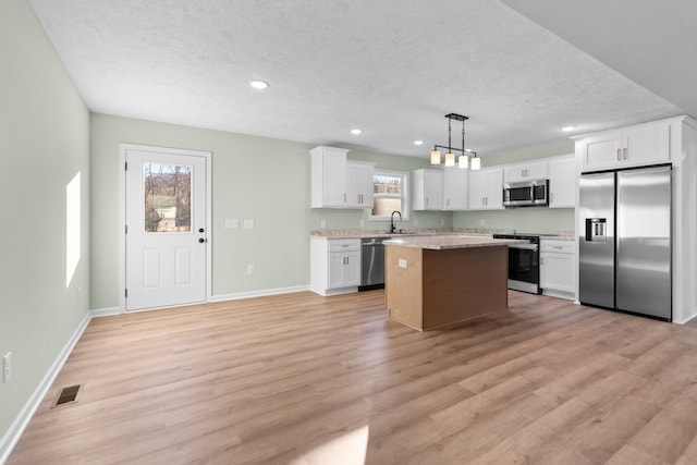 kitchen featuring stainless steel appliances, a center island, visible vents, and plenty of natural light