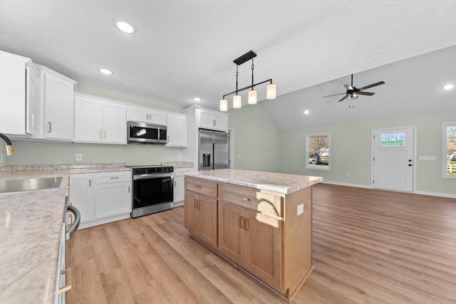 kitchen with light wood finished floors, appliances with stainless steel finishes, a sink, and a center island