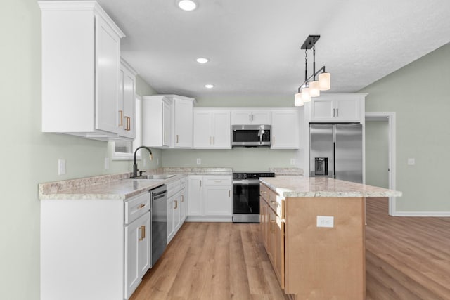 kitchen with appliances with stainless steel finishes, a center island, light wood-style floors, and a sink