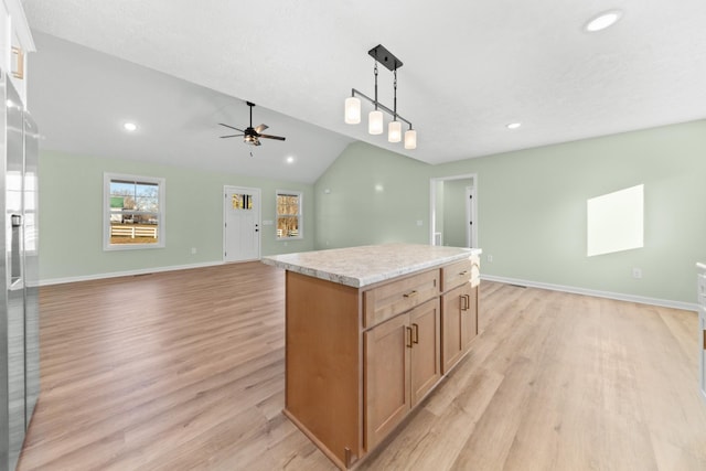 kitchen featuring open floor plan, pendant lighting, light wood-style flooring, and a center island