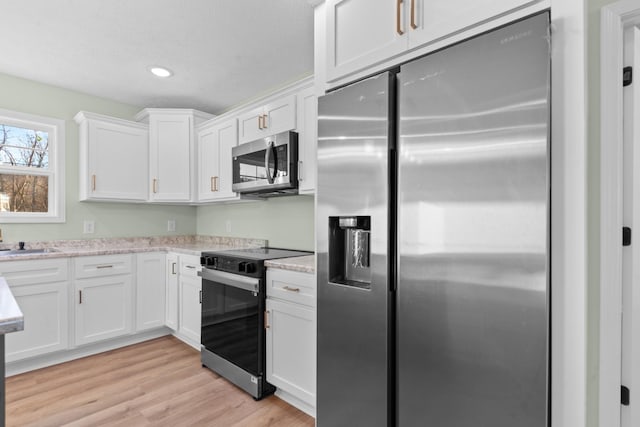 kitchen with light stone counters, recessed lighting, white cabinetry, light wood-style floors, and appliances with stainless steel finishes