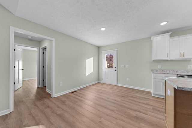 kitchen featuring white cabinets, light wood finished floors, baseboards, and light countertops