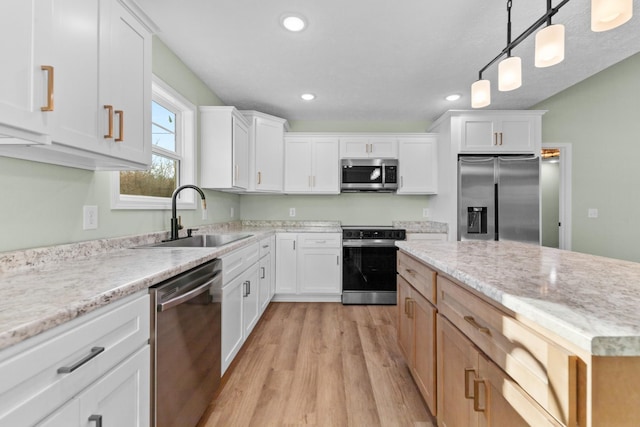 kitchen with recessed lighting, stainless steel appliances, a sink, white cabinets, and pendant lighting