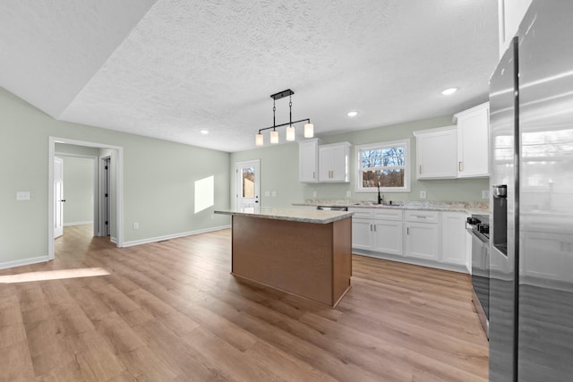 kitchen with light wood-type flooring, a center island, a sink, and stainless steel refrigerator with ice dispenser