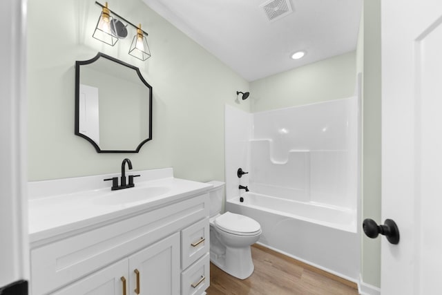 full bathroom with visible vents, toilet, shower / tub combination, wood finished floors, and vanity