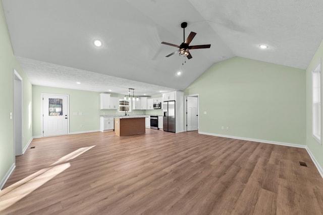 unfurnished living room featuring lofted ceiling, light wood-style floors, baseboards, and a ceiling fan