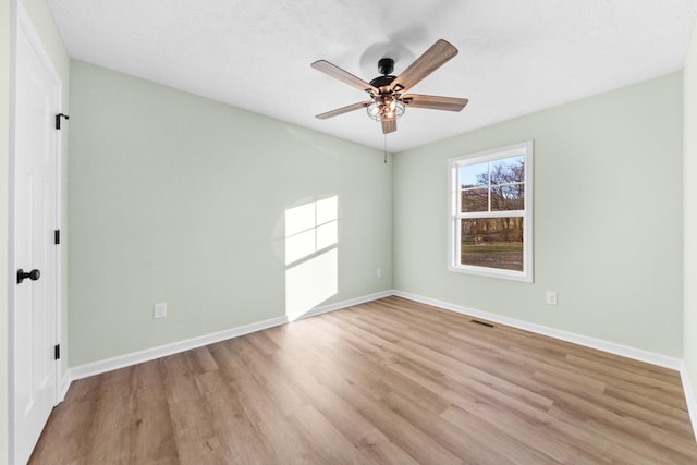 unfurnished room featuring light wood-type flooring, visible vents, baseboards, and a ceiling fan