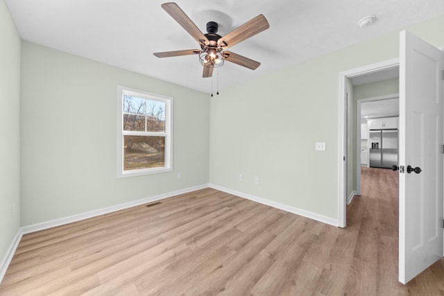 unfurnished bedroom featuring visible vents, baseboards, a ceiling fan, stainless steel built in fridge, and light wood-style floors