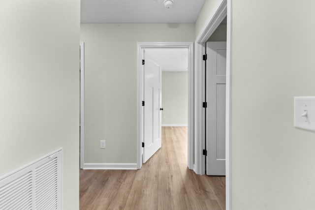 hallway featuring light wood-style floors, visible vents, and baseboards