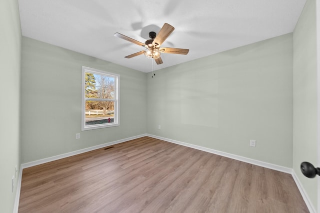 spare room featuring a ceiling fan, light wood-style flooring, and baseboards