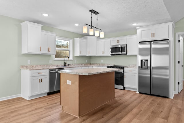 kitchen featuring a kitchen island, a sink, white cabinets, appliances with stainless steel finishes, and light wood-type flooring