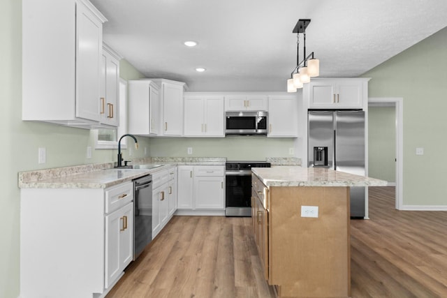 kitchen with light wood-style floors, appliances with stainless steel finishes, white cabinets, and a sink