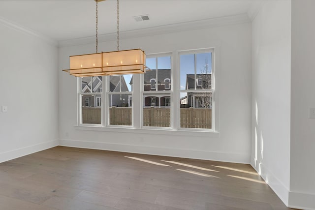 unfurnished dining area featuring ornamental molding, wood finished floors, visible vents, and baseboards