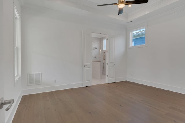 spare room featuring visible vents, crown molding, baseboards, and wood finished floors