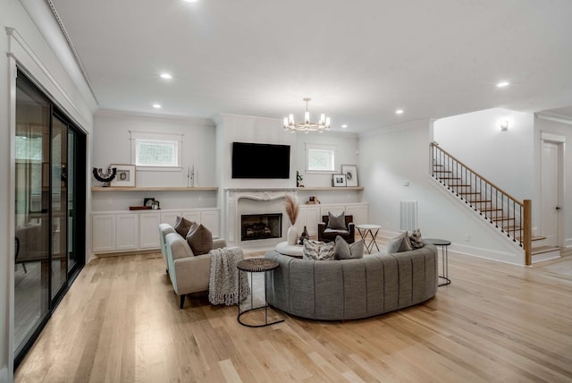 living room with an inviting chandelier, light hardwood / wood-style flooring, ornamental molding, and a high end fireplace