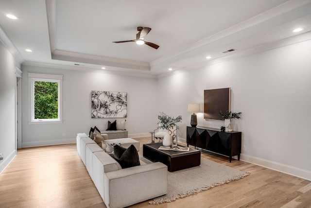 living room featuring ceiling fan, light hardwood / wood-style flooring, and a raised ceiling