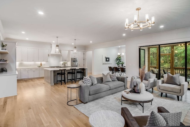 living room featuring an inviting chandelier, light hardwood / wood-style flooring, and sink