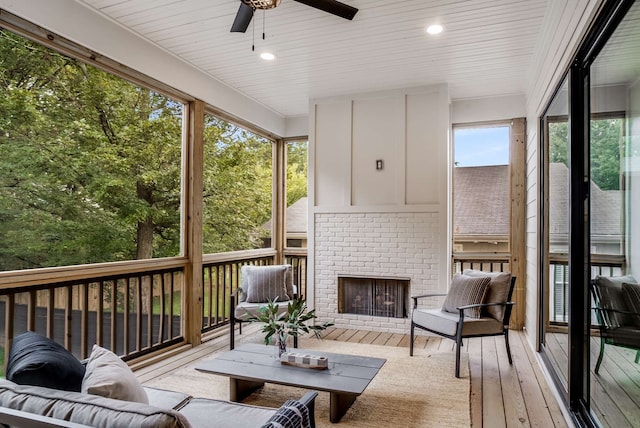 sunroom with ceiling fan, a brick fireplace, and a wealth of natural light