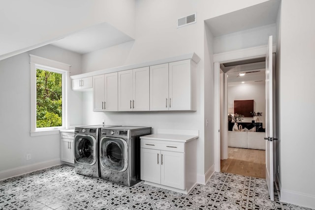 laundry area with cabinets, light tile patterned flooring, and washer and clothes dryer