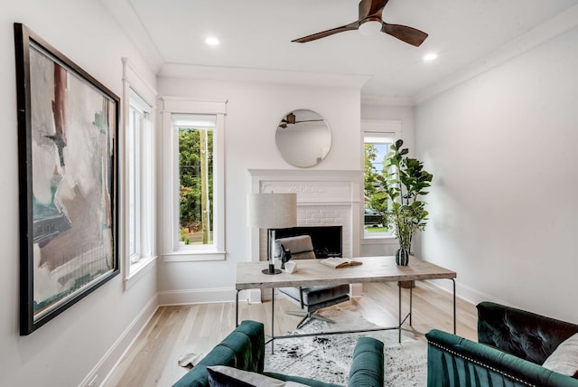 office featuring light wood-type flooring, a fireplace, ornamental molding, and ceiling fan