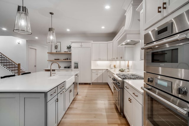 kitchen with a center island with sink, white cabinetry, pendant lighting, stainless steel appliances, and premium range hood