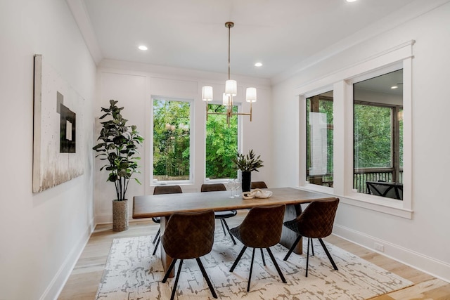 dining space featuring light hardwood / wood-style flooring, crown molding, and a chandelier