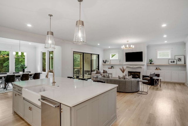 kitchen featuring pendant lighting, a center island with sink, light hardwood / wood-style flooring, and stainless steel dishwasher