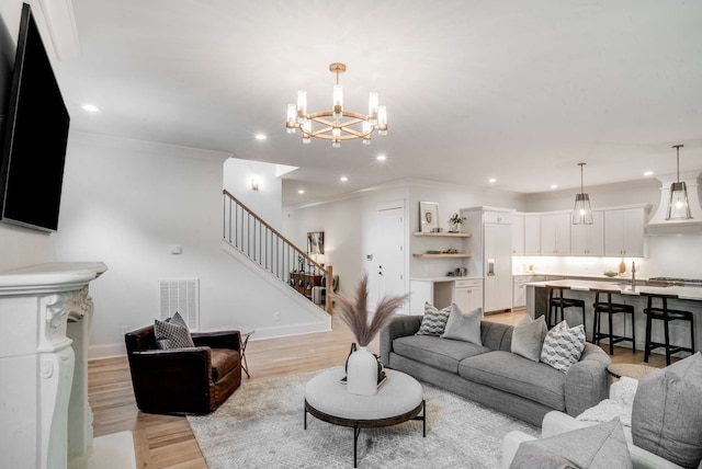 living room with light hardwood / wood-style flooring, a chandelier, and ornamental molding