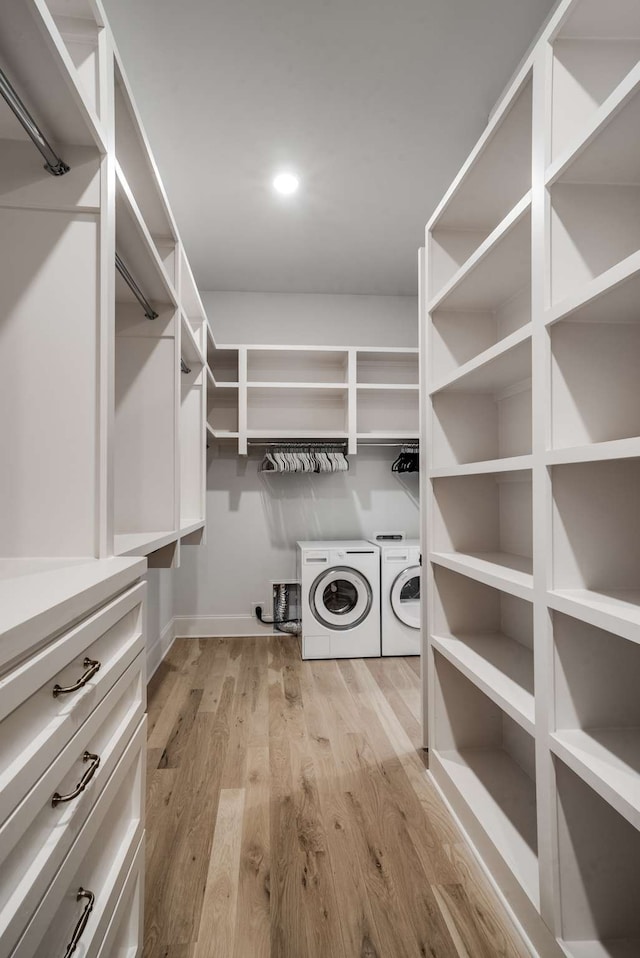 walk in closet with washing machine and clothes dryer and light hardwood / wood-style floors