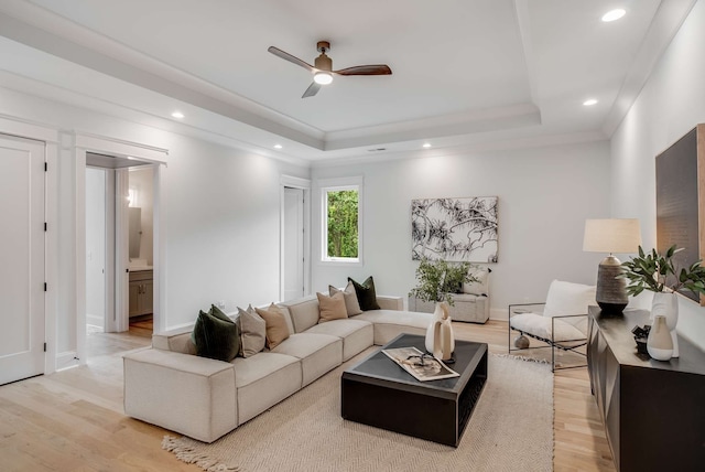 living room featuring a tray ceiling, light hardwood / wood-style floors, and ceiling fan