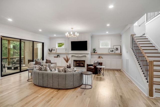 living room with light hardwood / wood-style flooring, a chandelier, a premium fireplace, and ornamental molding